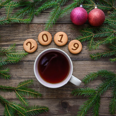 Christmas picture with the number 2019 on round cookies with a cup of tea on a wooden background