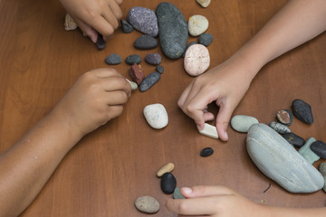 The child is playing with stones from children’s activities.kid draws something for her handcraft picture.