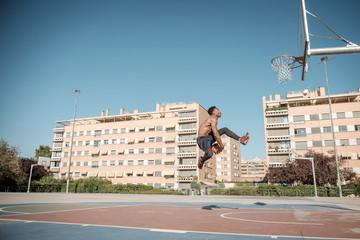 Afroamerican young man playing street basketball in the park
