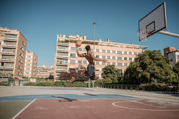 Afroamerican young man playing street basketball in the park