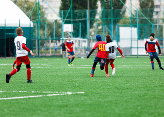football teams - boys in red, blue, white uniform play soccer on the green field. boys dribbling. dribbling skills. Team game, training, active lifestyle, hobby, sport for kids concept