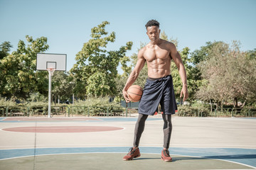 Obraz premium Afroamerican young man playing street basketball in the park