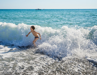 Little boy running out of the sea