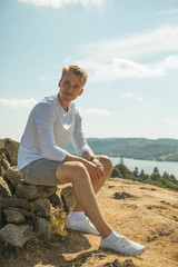 Fototapeta na wymiar Male Model Sitting on a Stone Cairn Overlooking Lake. Lake District UK.