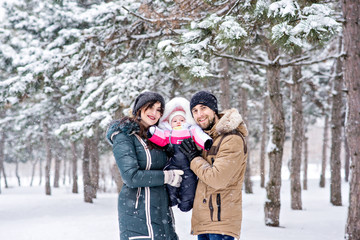 Fototapeta premium Beautiful young parents walk in nature with the baby in the snow