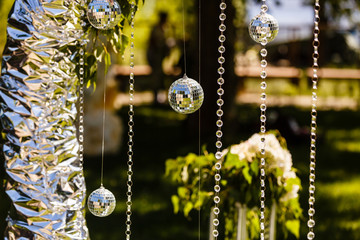 Fragment of creatively decorated wedding arch with hanging discoballs and glass beads