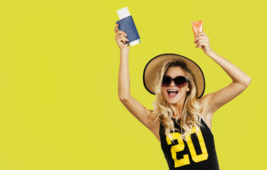 Travel concept. Very beautiful young girl with a passport, ticket and sunscreen, collected on holiday over yellow background.