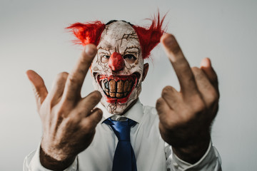 Closeup of a scary evil clown prepared for halloween, wearing a white shirt and blue tie. Thematic...