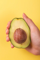 Half of avocado with kernel in female hand