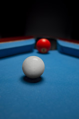 White and red billiard balls very close to the hole over blue felt