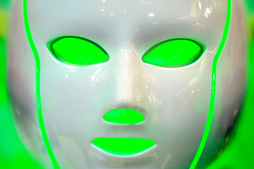 White facial mask for cosmetic procedures on a green background. Equipment for beauty salons. Cosmetology. Face care.