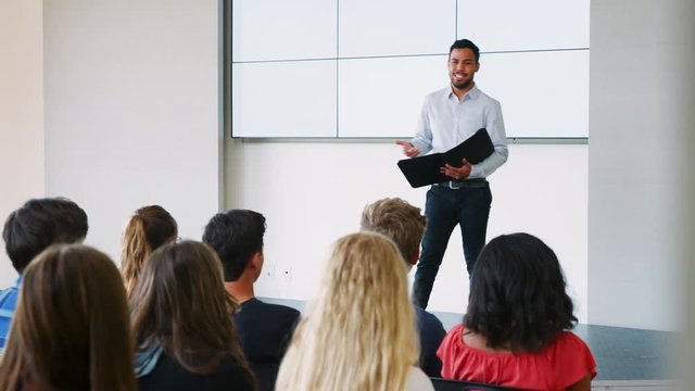 Teacher Giving Presentation To High School Class In Front Of Screen