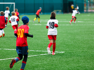 football teams - boys in red, blue, white uniform play soccer on the green field. boys dribbling. dribbling skills. Team game, training, active lifestyle, hobby, sport for kids concept
