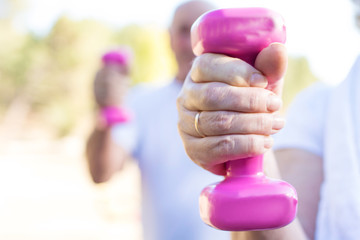 senior hand foreground with dumbbells