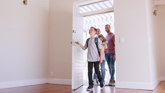 Slow Motion Shot Of Family Opening Door And Walking In Empty Lounge Of New Home