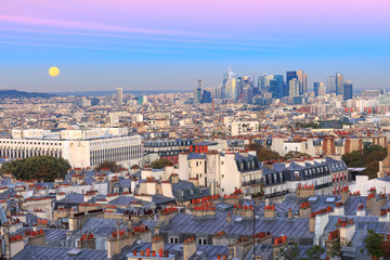 Obraz premium Aerial view from Montmartre over Paris roofs and La Defense business district with full moon at sunrise, Paris, France