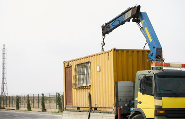 Crane truck unloading portable workers house container booth, outdoors