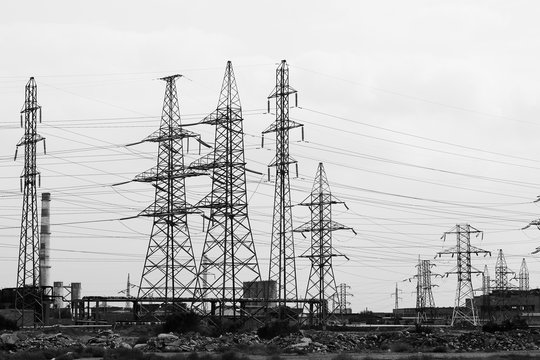 Electric poles with wires against the cloudy sky. Black and white photo of a High voltage post or High voltage towers, outdoors