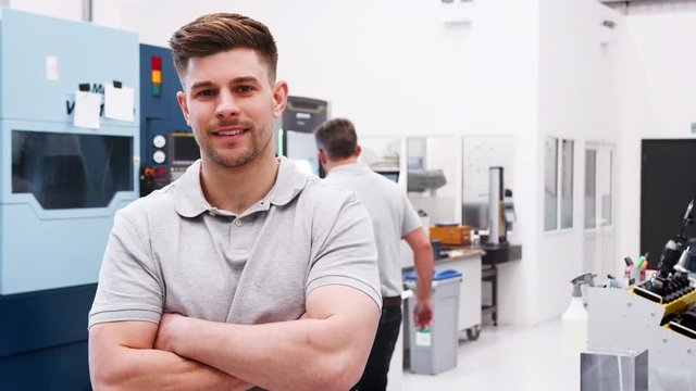 Portrait Of Male Engineer On Factory Floor Of Busy Workshop