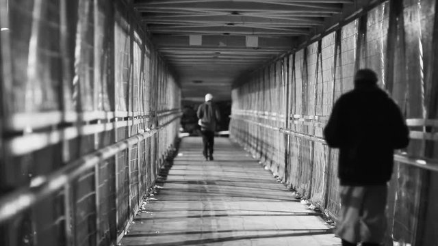 Drifters walking in long pedestrian tunnel at night in the dark