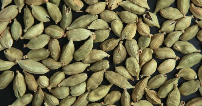 Green cardamom seeds rotating in slow motion top view