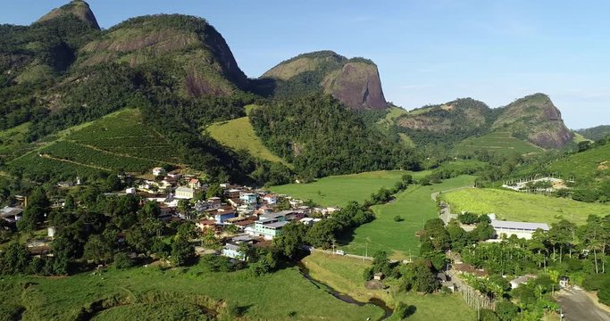 Drone zoom out scene from rural landscape. Small houses in the middle of the forest. On the background mountains and blue sky.