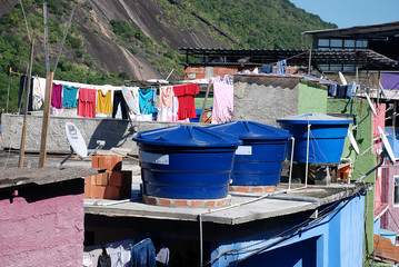 Fototapeta na wymiar Water tanks on the roof of a house in a favela on the hillside of a steep hill on the outskirts of Rio de Janeiro, Brazil