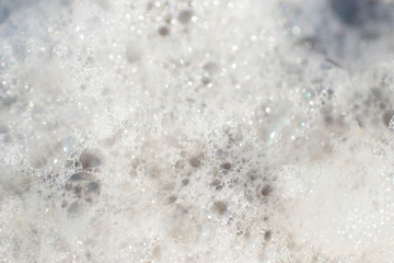 Unusual and very beautiful sea foam on the background of a sandy clean beach on a bright and sunny summer day