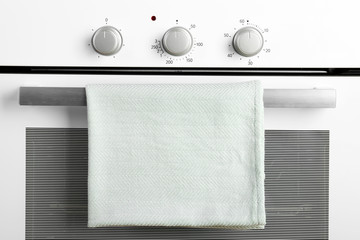 Modern electric oven with towel, closeup view