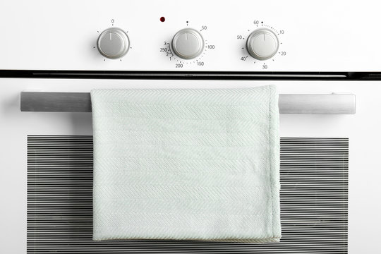 Modern electric oven with towel, closeup view