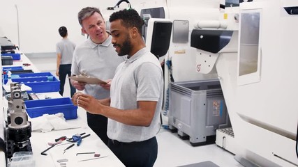 Engineer And Male Apprentice Measuring Components In Hi Tech Engineering Plant