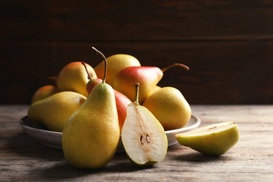 Ripe pears on wooden table against dark background
