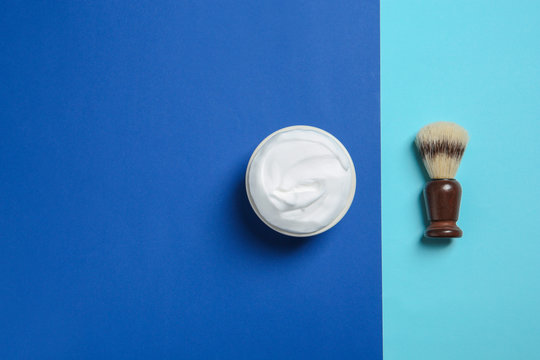 Flat lay composition with shaving brush and cream on color background. Space for text