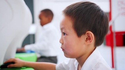 Asian schoolboy using computer at a science centre, close up - Powered by Adobe