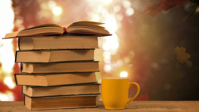 Books and coffee cup against falling autumn leaves and bright background 4k