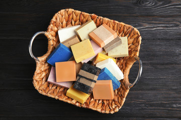 Many different handmade soap bars in wicker basket on table, top view