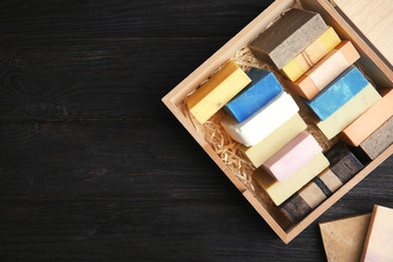 Many different handmade soap bars in wooden box and space for text on table, top view