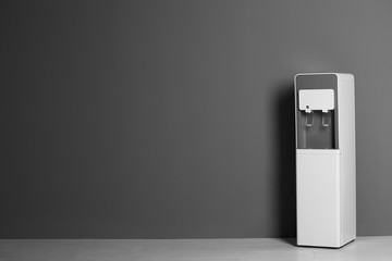 Modern water cooler against gray wall with space for text
