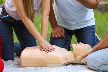 Obraz na płótnie Canvas Woman practicing CPR on mannequin at first aid class outdoors