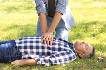Passerby performing CPR on unconscious man outdoors. First aid