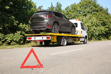 Emergency stop sign with broken car and tow truck on background