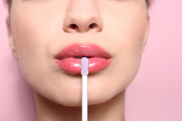 Beautiful young woman applying gloss on her perfect lips, closeup - obrazy, fototapety, plakaty