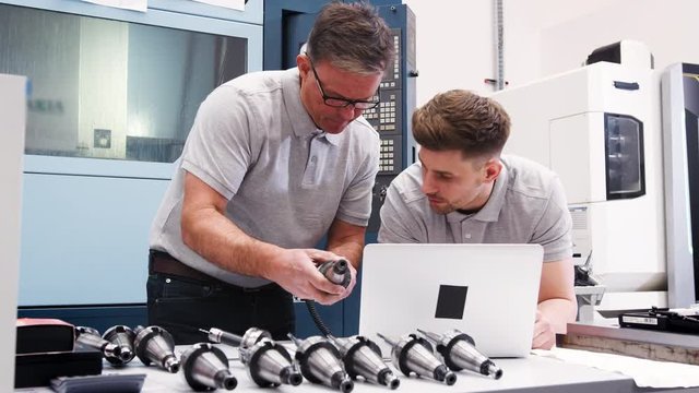 Engineer Showing Apprentice How Use CAD Software On Laptop 