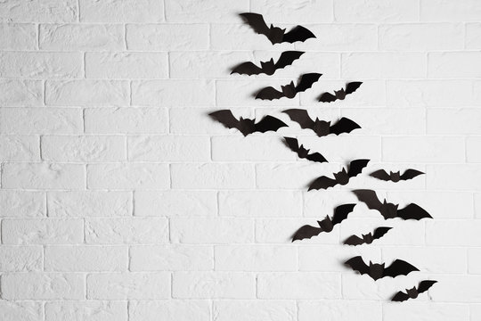 Paper bats on brick wall with space for text. Halloween decor