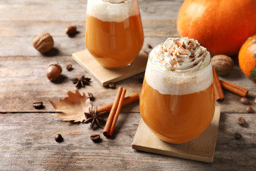 Glasses with tasty pumpkin spice latte on wooden table