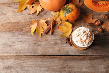 Flat lay composition with cup of pumpkin spice latte and space for text on wooden table