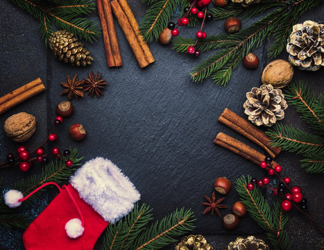 Christmas or New Year dark background, frame, template, with festive decorations, winter spices and Christmas decorations, nuts and fir branches, top view