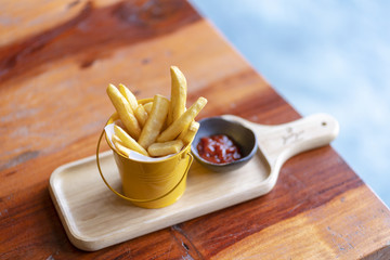French fries and ketchup on wood board background.