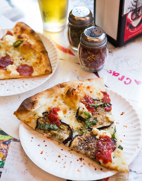 Eggplant pizza with chili flakes on a paper plate.
