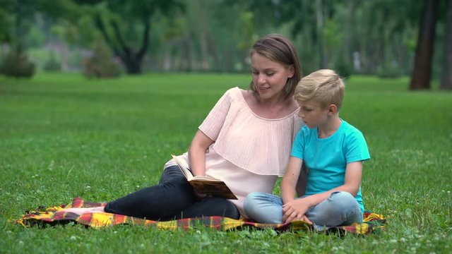 Mother and son doing homework together in park, child education, parenthood